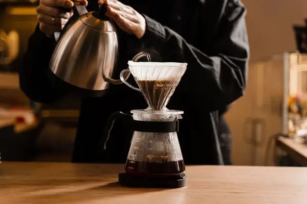 Person gießt heißes Wasser über Kaffeepulver in einem Filter. Die richtige filterkaffee temperatur ist entscheidend für den Geschmack.